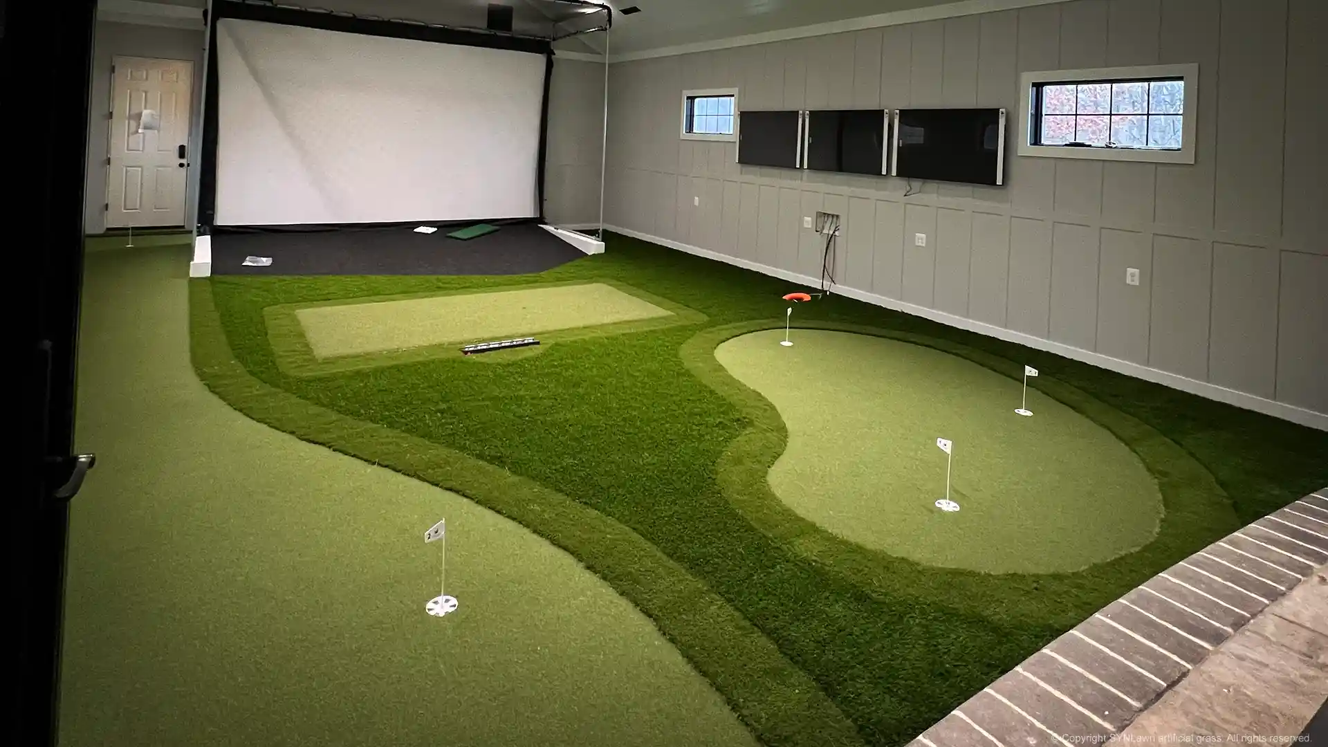 Dream indoor golf practice facility with custom putting green and golf simulator installed by SYNLawn image of an indoor golf simulator with custom putting green by SYNLawn Golf