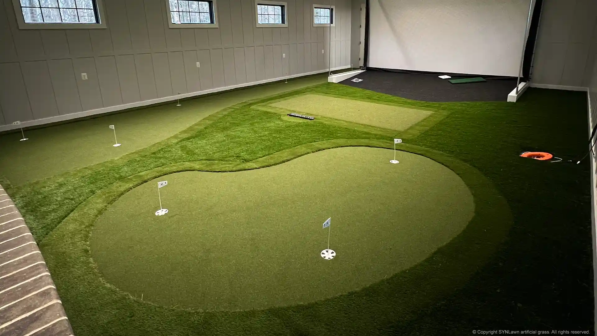 Dream indoor golf practice facility with custom putting green and golf simulator installed by SYNLawn image of an indoor golf simulator with custom putting green by SYNLawn Golf